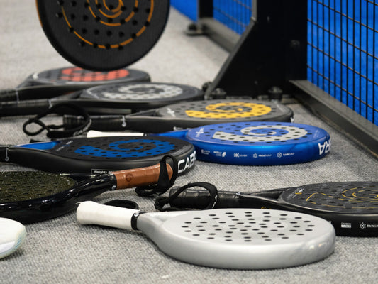 Padel rackets die bij de kooi liggen.