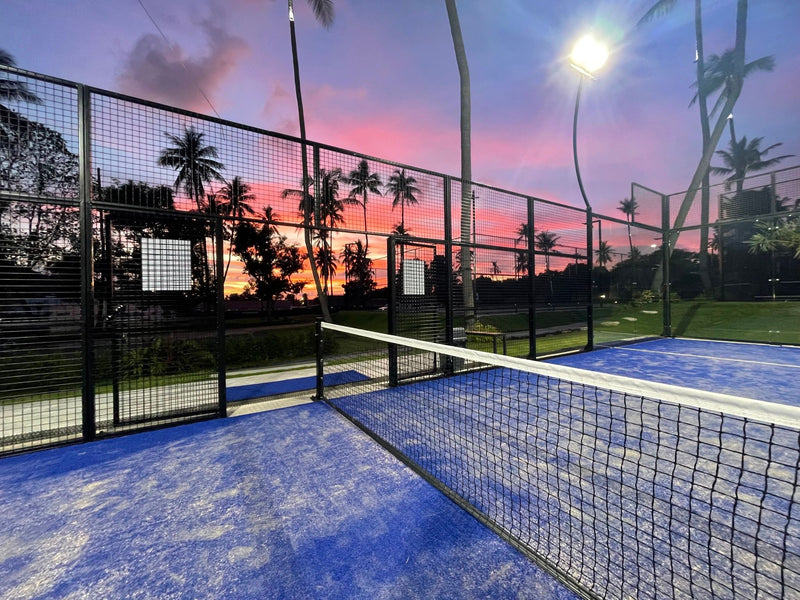 Padel Hunt – online padel racket kopen met topmerken en snelle levering. POV op padelbaan bij zonsondergang.